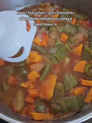 The cover image shows a close-up view of a cooking pot filled with soup. The soup contains visible chunks of vegetables, including orange carrots and green beans, in a reddish broth. A white hand mixer is partially visible, submerged in the soup, with text overlay. The composition is focused on the soup and the cooking process.