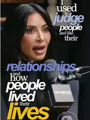 The image showcases Kim Kardashian speaking into a microphone which is branded, overlaid with overlaid text. The background is dark, with some indistinct shapes suggesting a studio setting. Text overlayed on the image states "I used to judge people and like their relationships and how people lived their lives". The image has a studio lighting setup.