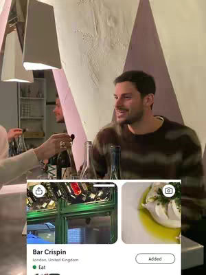 A man smiling inside a stylish bar, with a minimalist design and an app overlay showing a restaurant listing and a food photo.