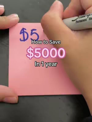A hand holding a black marker writes on a pink sticky note. The text is in dark blue marker, and the headline below the text is in a pink hue.