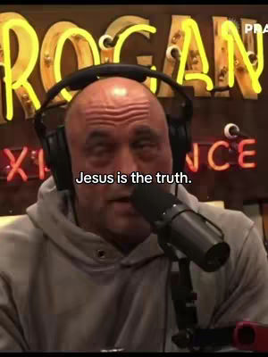 A bald man with headphones and a grey hoodie is speaking into a microphone. Behind him are yellow neon lights spelling out "ROGAN" and red neon lights underneath that spell out the word "ENCE". Text overlayed on the image reads "Jesus is the truth."