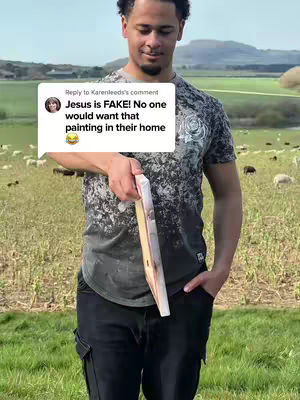 A man stands in a grassy field, holding a painting that's propped up. Behind him is a field with sheep grazing and distant hills. The man appears to be smiling slightly. A text overlay appears to the left of his head.
