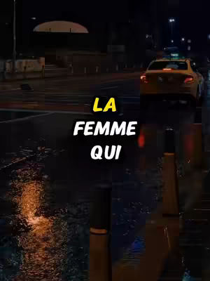 A night scene showing a road, a taxi, and text overlayed. Rain is visible on the ground and light reflections are visible.