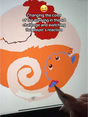 A digital drawing of an orange creature with large eyes is shown on a tablet screen, positioned over a drawing surface. Above the creature, a text overlay indicates the content involves changing the color of the drawing in an art challenge. A playful emoji is positioned above the text to show the creator's reaction.