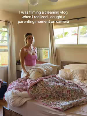 The cover image shows a woman in a bedroom, standing in front of a bed with a floral-patterned quilt. She is holding a pillow and the background is a window and white curtains. Text in the upper area of the image says, 'I was filming a cleaning vlog when I realized I caught a parenting moment on camera'.
