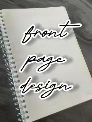 A notebook lies open, angled, with a spiral binding visible along the left edge. The top page is slightly darker. Overlaid, there is a text that reads 'front page design' in a cursive font.