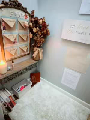 An indoor shot depicts a prayer room or a dedicated space for spiritual reflection. The room features a plush white rug, a display for prayer notes, dried flowers, and a candle.