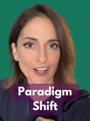 A woman with brown hair and light skin is centered in the frame, seen from the chest up. Behind here is green background. The image has a text overlay in the lower-center with the words "Paradigm Shift".