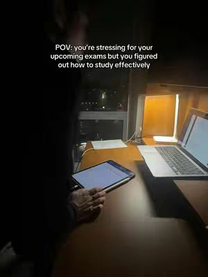 A dimly lit room with a desk, laptop, and tablet. The text 'POV: you're stressing for your upcoming exams but you figured out how to study effectively' is overlaid on the image. The overall composition suggests a study environment.
