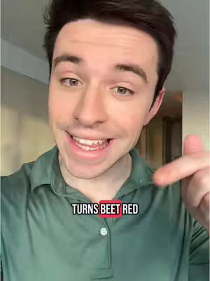 A man with brown hair is shown from the chest up, smiling and pointing to his right with his right index finger, there is text overlayed on the image.