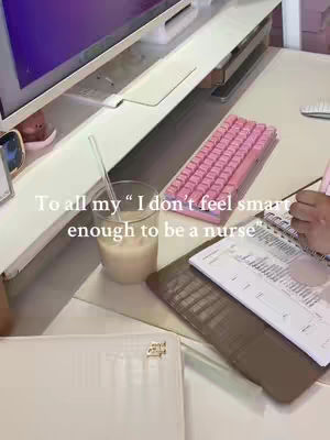 The cover image shows a workspace. There's a glass of a milky drink with a straw, a pink keyboard, some papers on a desk, and a computer monitor in the background. The text overlay in the image suggests the creator feels inadequate to the nursing profession. Various items related to studying nursing are visible.