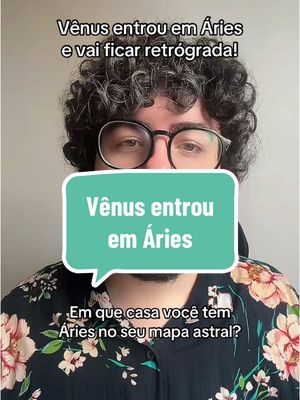 The cover image shows a man with curly hair and glasses, framed from the chest up. A speech bubble stating the title of the video, which says "Vênus entrou em Áries" in a green rounded rectangle is covering his face. The background is a plain wall and the man is wearing a shirt with a floral pattern.