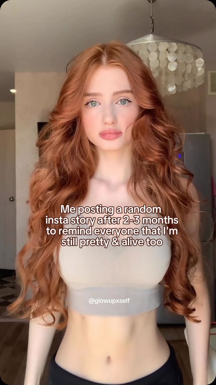 A young woman with long, wavy red hair and light skin is the central focus. She wears a beige crop top and is positioned in front of a blurred background, likely indoors. Text overlays are added to the image, giving it a modern and social media aesthetic.