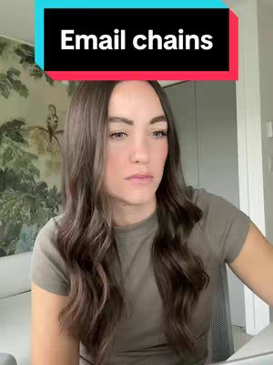 A woman with long brown hair is looking downwards with a bored facial expression. She is wearing a light green shirt. Behind her is a room with art on the walls. Over her head, black text boxes on top of a red band say "Email chains".