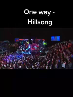 The cover image shows a live concert scene. The foreground is filled with a crowd of people, and the stage is visible in the middle ground. The lighting is dim, with colorful stage lights illuminating the band, and the stage is set up with a screen in the background. The text overlay at the top indicates the name of the artist and song.