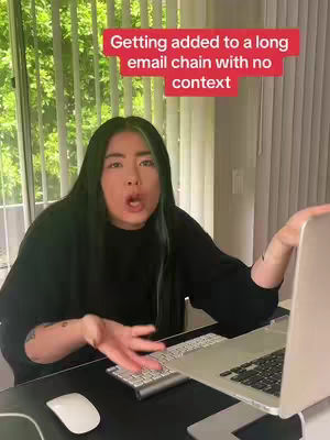 A woman with long dark hair, black top, and a surprised expression sits at a desk with a laptop and mouse. A red text box at the top says, Getting added to a long email chain with no context.