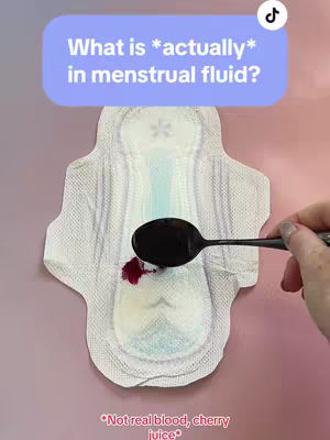 The image features a sanitary pad with a spoon and some red liquid on top. A purple-blue speech bubble with white text overlay is on top.