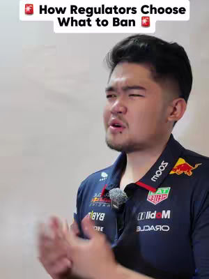 A medium shot of a man talking, with text overlaid at the top. The man is wearing a dark blue collared shirt with logos on it. He has short, dark hair and is looking to the side while talking or making a point.