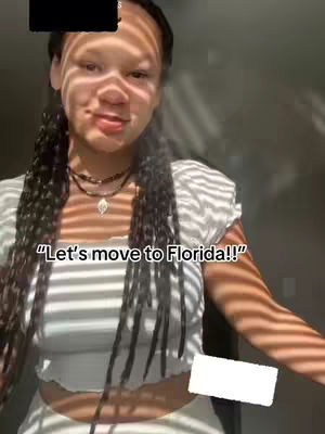 The cover image features a young woman with long dark braids, smiling slightly. She wears a white top. Text overlayed says, "Let's move to Florida!!" The lighting creates striped shadows across her face and body.