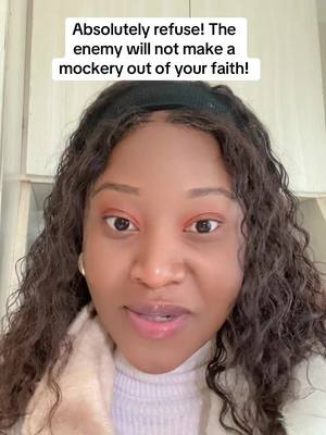 A close-up selfie featuring a woman with dark, curly hair and a warm expression. She has brown eyes and is looking slightly off-center. The image is mostly of her face and upper body, with a soft, neutral-colored background. Text overlay, in a white box, says the video is about refusing to let the enemy make a mockery of faith, with a call for the viewer to believe.