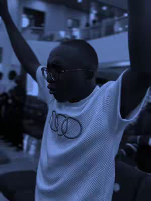 The cover image showcases a man with arms raised, expressing a joyful and worshipful pose. The image is heavily tinted in a blue/purple hue, giving it a cool, somewhat somber atmosphere. He is wearing glasses and a white t-shirt with a logo. The background appears to be a large open space, possibly a hall.