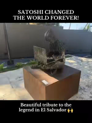The cover image shows a statue of a person sitting at a laptop. The statue is made of metal and is silver in color. It is placed on top of a large, brown rectangular base. The background is blurry, but appears to be a building and some greenery. The image has text overlays in the top and bottom sections.