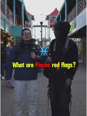 Two men are filmed outside in a pedestrian area. One wearing glasses and a jacket with a microphone. The second figure is darker and facing the camera with their back to the camera. Text overlayed on the image asking about Pisces red flags.