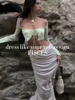 A woman in a light green top and a light gray skirt poses against a rocky background. The text overlay reads, "dress like your venus sign" and "Pisces".