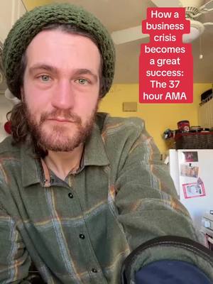 The cover image features a man with a beard wearing a green beanie and a plaid shirt. Text overlays in red announce 'How a business crisis becomes a great success: The 37 hour AMA'. The man is framed in a medium shot, with a yellow background behind, and a white refrigerator visible in the upper right corner. The shot appears to be taken indoors.