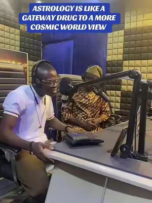 The image shows a man wearing glasses and a headset, speaking into a microphone, with another person in the background, and the overlay text: Astrology is like a gateway drug to a more cosmic world view.