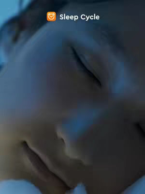 A close-up shot features the side profile of a person's face in a dimly lit environment. The person, whose features are soft, with closed eyes and a slight curve to the lips, appears to be asleep. The background is a dark shade of blue, creating a serene ambiance. The app logo appears on top left.