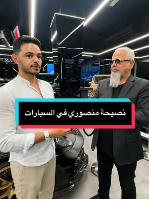 The image showcases two men in what appears to be a car showroom. The foreground features a man in a white shirt and khaki pants, holding something. Behind him, another man in a suit and glasses is present. In the background, cars are partially visible, alongside a black text box with Arabic text.