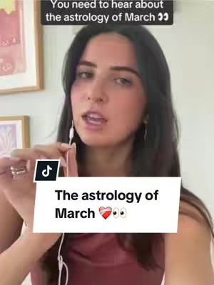 A person with dark hair and earrings is holding a wired earphone. A text box appears in the front that says 'The astrology of March' with heart and eyes emojis. In the background there are some abstract art framed.