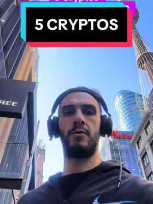 A man wearing headphones stands in front of a street backdrop with tall buildings, and a text overlay that reads "5 CRYPTOS". The sky is bright blue.
