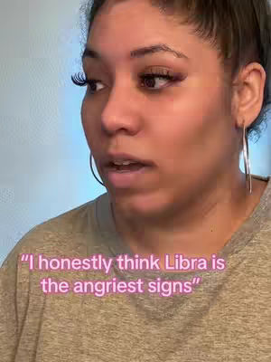 The cover image is a close-up shot of a woman's face. She has dark hair pulled back, large hoop earrings, and is wearing a light-colored t-shirt. The background is a blurry, light-colored wall. Text overlayed on the image reads, "'I honestly think Libra is the angriest signs'".