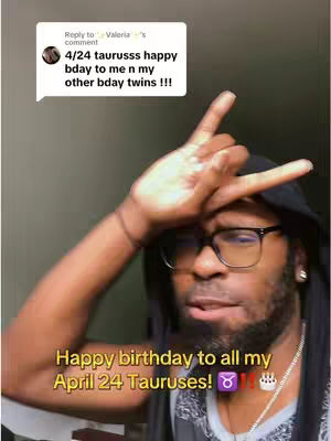 A selfie-style video cover image featuring a Black man with a beard. He's wearing glasses and a black hoodie, positioned against a muted, neutral background. The man is making a hand gesture, with the index and middle fingers extended. Text overlaid in a yellow color reads "Happy birthday to all my April 24 Tauruses!" indicating the video's subject is related to the Taurus zodiac sign and birthday wishes. A speech bubble with white background and a text inside it are in the upper left corner, likely related to a comment.
