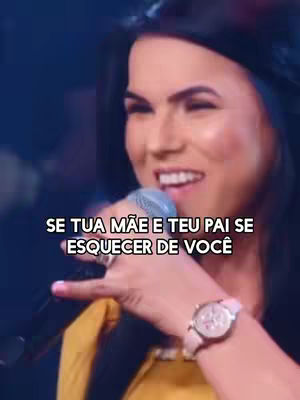 A woman with long dark hair is singing into a microphone. The background is a blurry dark blue. She's wearing a yellow shirt and a watch. The text overlay is in white font, positioned at the bottom, reads: SE TUA MÃE E TEU PAI SE ESQUECER DE VOCÊ