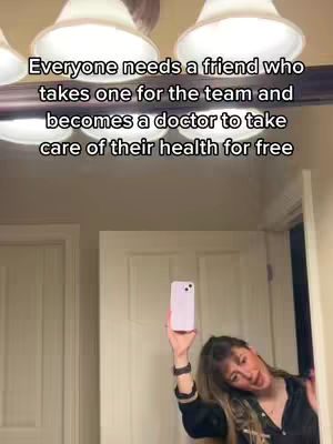 A woman is taking a selfie in a bathroom with the image overlaid with text, holding up a light purple phone. The background includes bright overhead lights above a mirror and white closet doors.