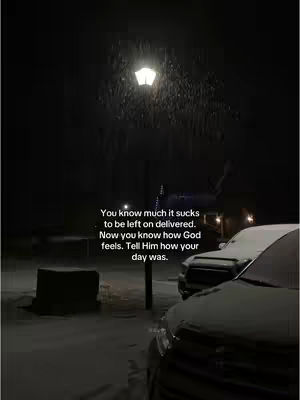 A nighttime winter scene with falling snow. A street lamp illuminates the scene, with snow-covered vehicles parked on the right side of the image. There's a dark structure on the left, and text overlayed in the center.