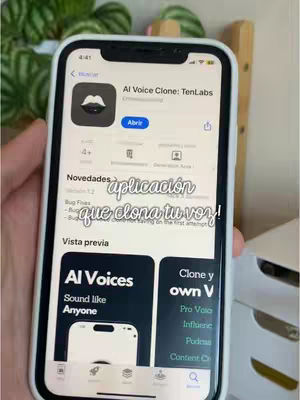 A hand holding a smartphone showing the App Store page for an app called AI Voice Clone. The app icon is a stylized mouth with a black background. Overlayed text is handwritten in a cursive font that says 'aplicación que clona tu voz!'