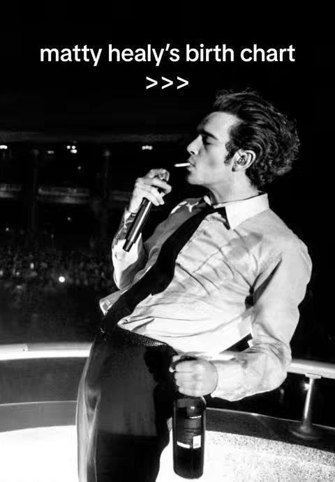 A black and white image of a man smoking a cigarette and holding a microphone and a bottle. He is on a stage in front of a crowd. There is text overlayed on top.