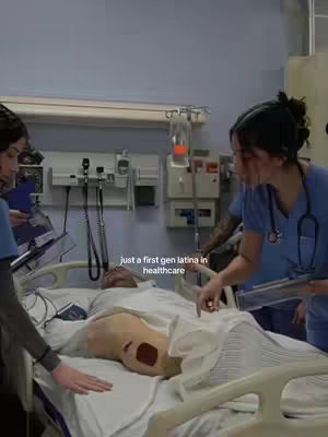The cover image shows a hospital room scene with several people around a patient in a bed. The central focus is a medical training dummy lying on the bed with visible wounds. Two women, wearing scrubs, are on either side of the bed, looking and gesturing toward the dummy. The room includes medical equipment, and the overall lighting is bright, typical of a hospital setting. The text overlay reads, 'just a first gen latina in healthcare'.