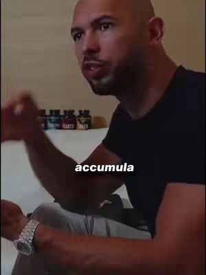 A bald man with a goatee in a black shirt is speaking, with the word "accumula" superimposed on the image. He has a luxury watch on his left wrist.