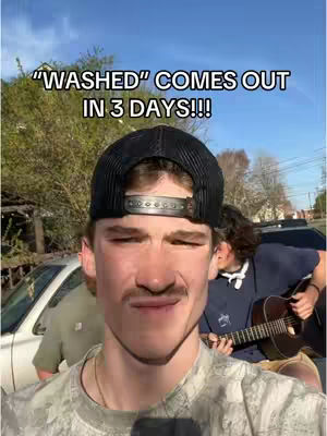 A young man with a mustache and a black cap is centered in the image, looking at the camera with a slight pout. The text overlay states, “WASHED” COMES OUT IN 3 DAYS!!!“. A car and trees are in the background.