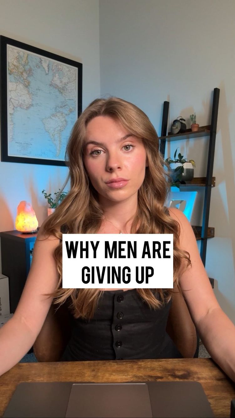 A woman with long wavy brown hair is seated in front of a desk with a world map on the wall behind her. A text overlay, "WHY MEN ARE GIVING UP", is placed at the center of the image.
