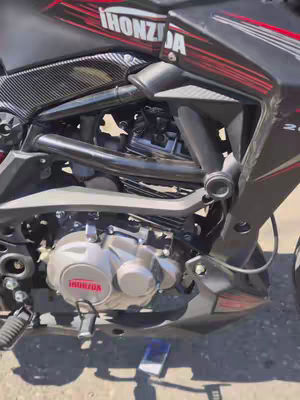 A close-up shot of a black and red motorcycle's engine and frame. The brand name "HONDA" is visible on the engine casing. The frame is black with red accents, and various mechanical components are visible.