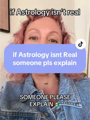 A selfie-style video with a light-skinned woman with pink curly hair and a blue denim jacket is the centerpiece. She is looking up at the camera, with the top of her forehead partially obscuring the shot. A light blue rectangular text overlay is present. Below the text, text in a white box reads, "SOMEONE PLEASE EXPLAIN", with a small flag beside it.