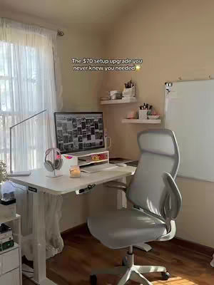 The cover shows a well-lit home office setup. A white standing desk holds a laptop, headphones, and a candle. An ergonomic gray chair is pulled up to the desk. The background shows a window, and shelving. Light beige walls complete the setting.
