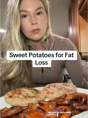 A woman with long blonde hair is looking at the camera. She's wearing a beige top and in front of her is a plate of grilled food. The text overlay reads 'Sweet Potatoes for Fat Loss'.