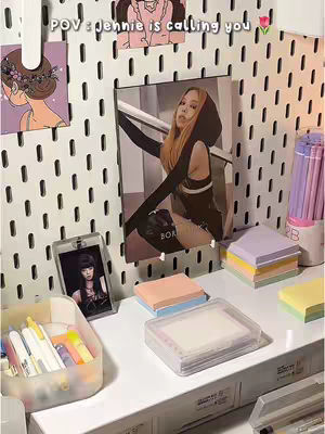 The cover image shows a white pegboard with various items attached. A large picture of Jennie from Blackpink is centrally displayed. Below it sits a small picture of Jennie in a clear case. The foreground contains stationery and sticky notes. The text overlay says, "POV: Jennie is calling you."